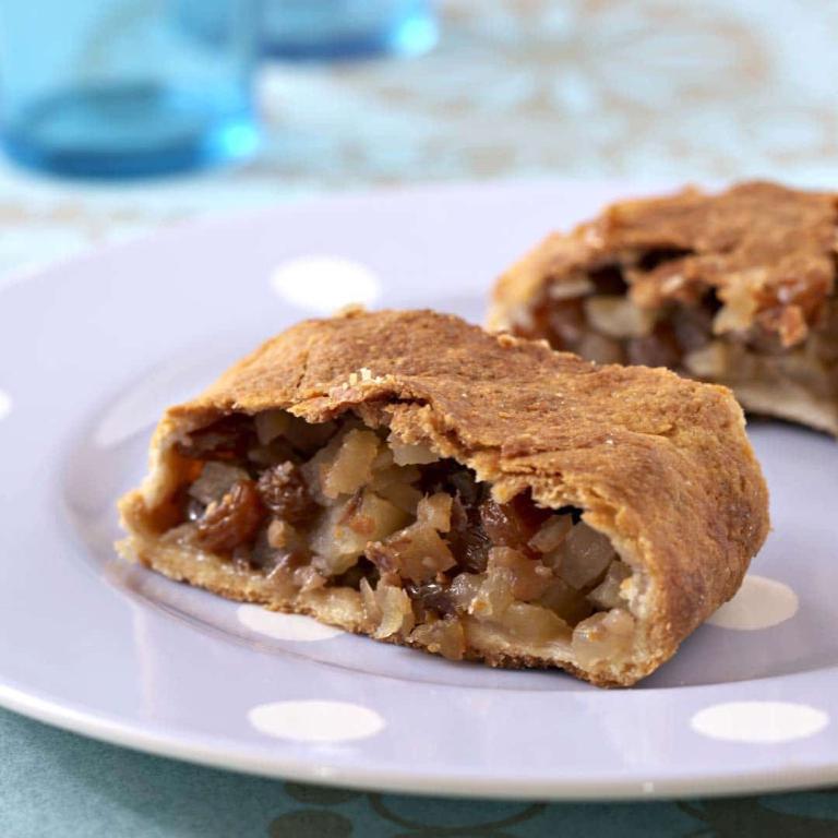 sur une assiette blanche, deux morceaux d'apfelstruedel, avec la croûte de pâte fine qui englobe des morceaux de pommes coupées et des raisins secs
