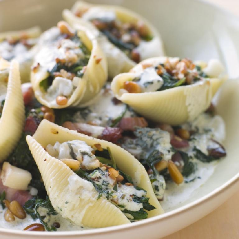 une assiette avec des pâtes conchiglioni farcies aux épinards et des pignons de pin