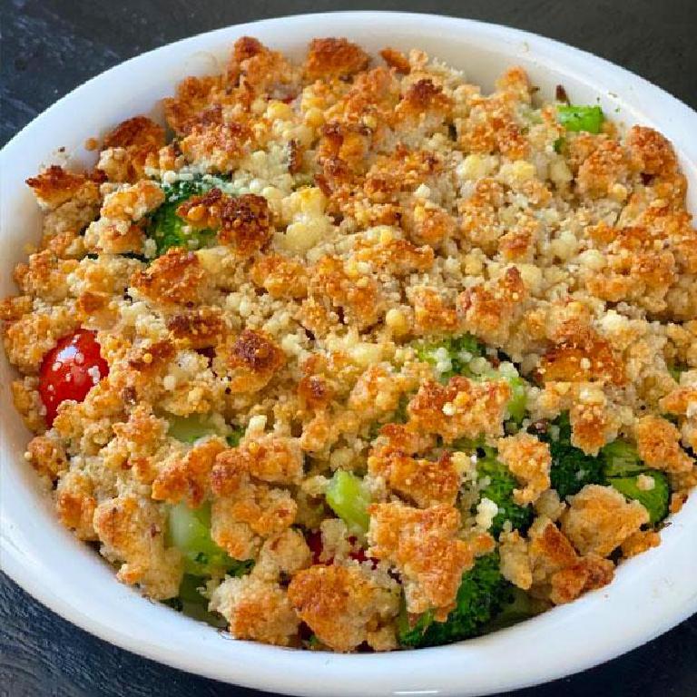 Un assiette avec un crumble au brocoli et aux tomates cerises