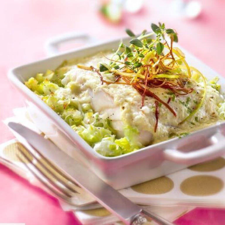 dans une assiette, un dos de cabillaud poché sur un lit de fondue de poireaux et des poireax frits dessus
