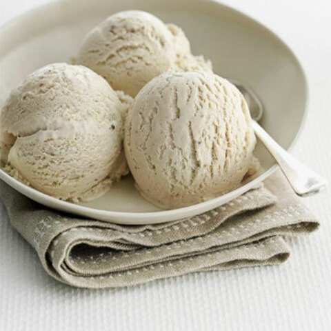 une assiette posée sur un torchon avec trois boules de glace à la banane et une cuiller prête à déguster...