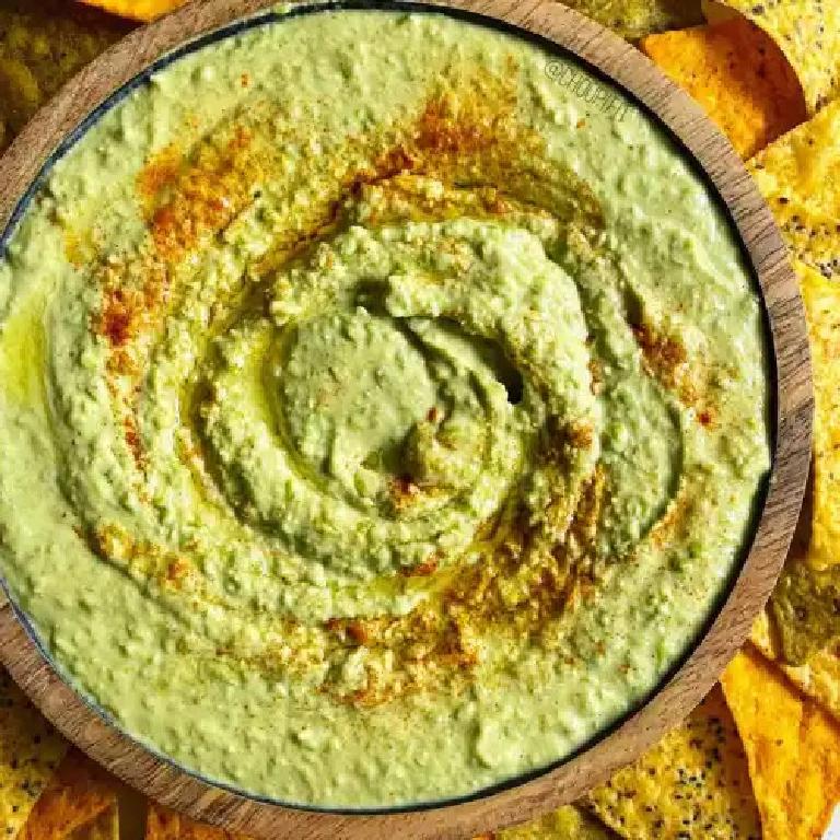 un plat de houmous de petits pois parsemé d'épices