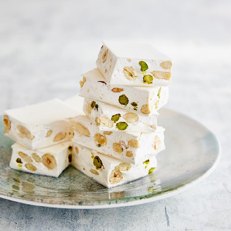 une assiette avec des morceaux de nougats blancs empilés