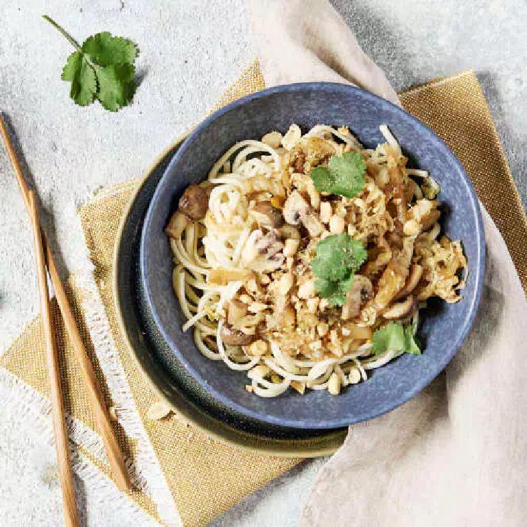 un bol de nouilles chinoises sautées avec du chou et des champignons shiitaké