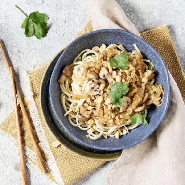 un bol de nouilles chinoises sautées avec du chou et des champignons shiitaké