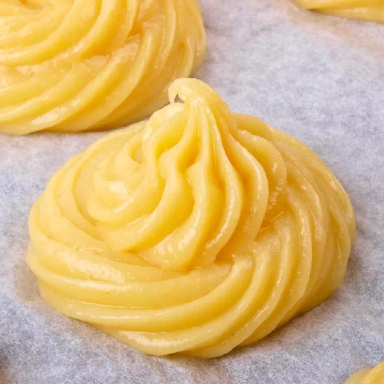 de la pâte à choux disposée sur une plaque de pâtisserie avant cuisson