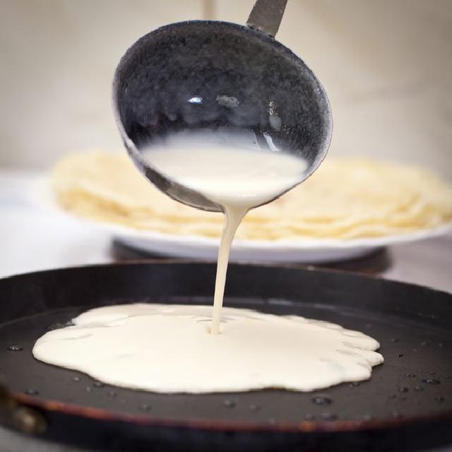 une poêle dans laquelle on verse à la louche de la pate à crêpes