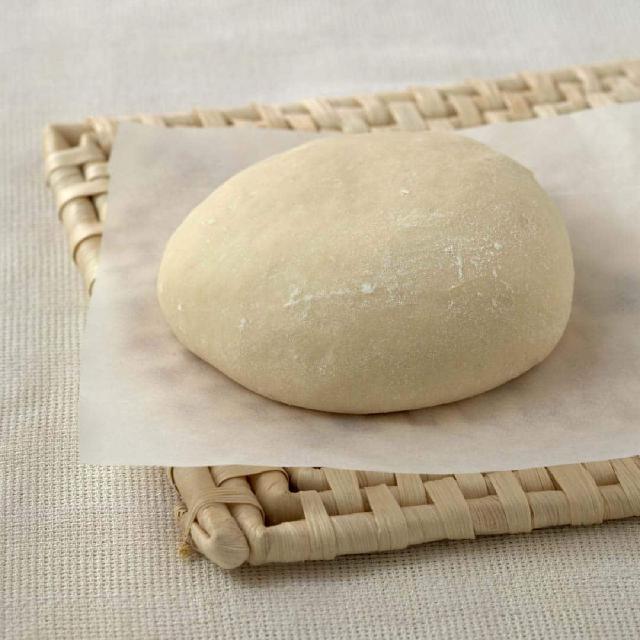 photo d'une boule de pâte à pizza posée sur une planche et farinée.
