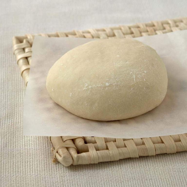 photo d'une boule de pâte à pizza posée sur une planche et farinée.