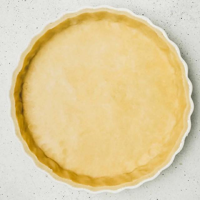 un moule à pâtisserie avec un fond de pâte brisée non cuite