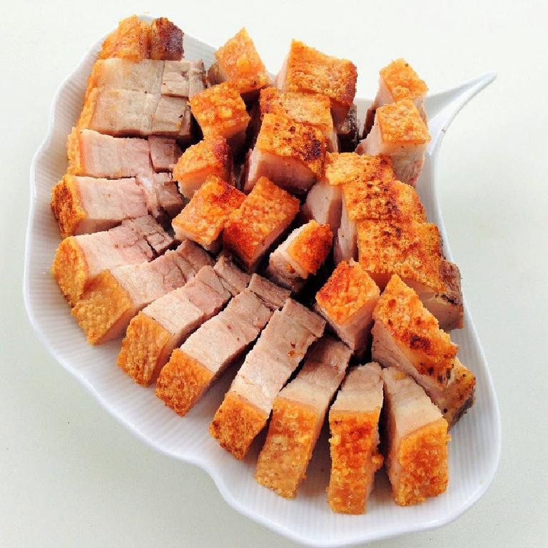 des morceaux de porc laqué croustillant dans une assiette blanche