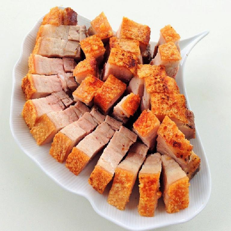 des morceaux de porc laqué croustillant dans une assiette blanche