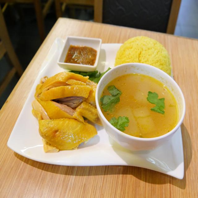 Des morceaux de poulet cuisiné façon hainan, avec du riz et un bol de bouillon