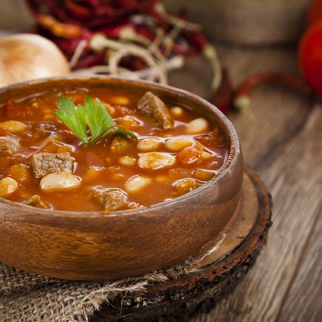 Un plat en terre cuite rempli de ragoût d'agneau avec des haricots blancs