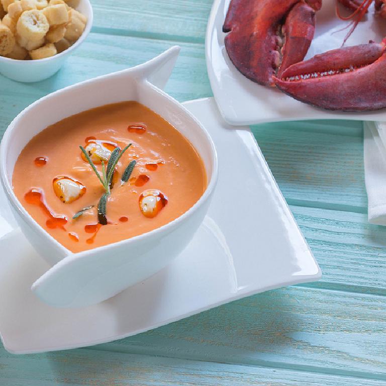 Un bol de sauce homardine et des pinces de homard sur une assiette