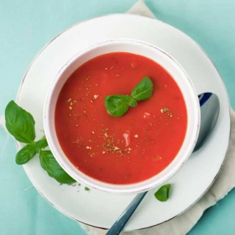 une assiette de soupe de tomate avec une feuille de basilic