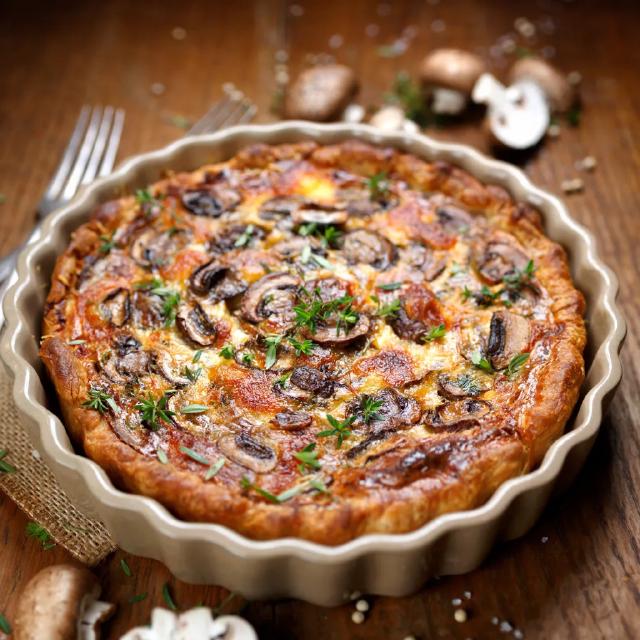 Une tarte aux champignons dans son plat, prête à être servie