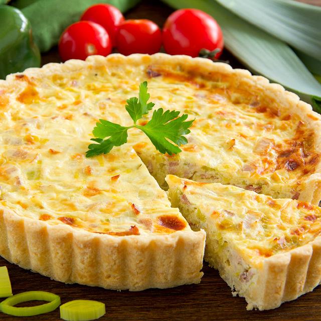 Une tarte aux poireaux sur un plat, avec une part déjà découpée
