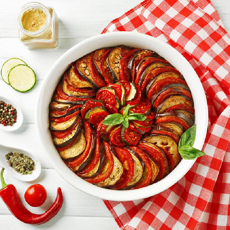 Un plat en terre cuite avec un tian de légumes chaud