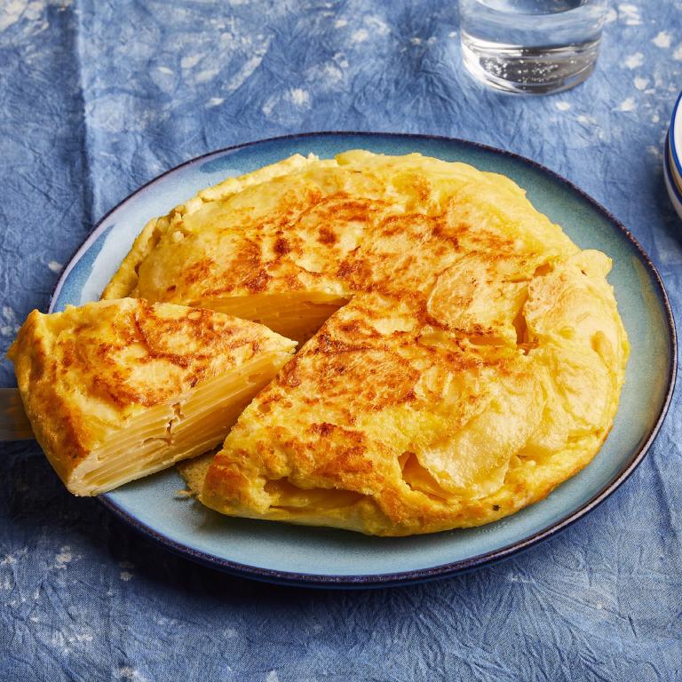 Une tortilla de patatas sur son assiette, avec une part déjà coupée