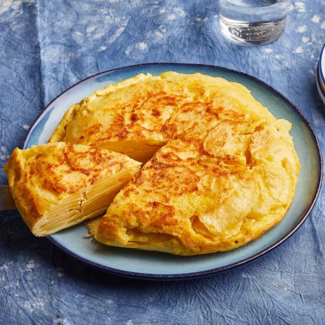 Une tortilla de patatas sur son assiette, avec une part déjà coupée